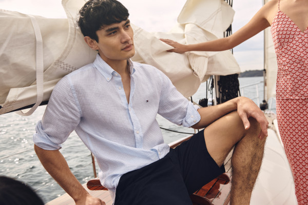 Model wears Tommy Hilfiger shirt and shorts on a boat